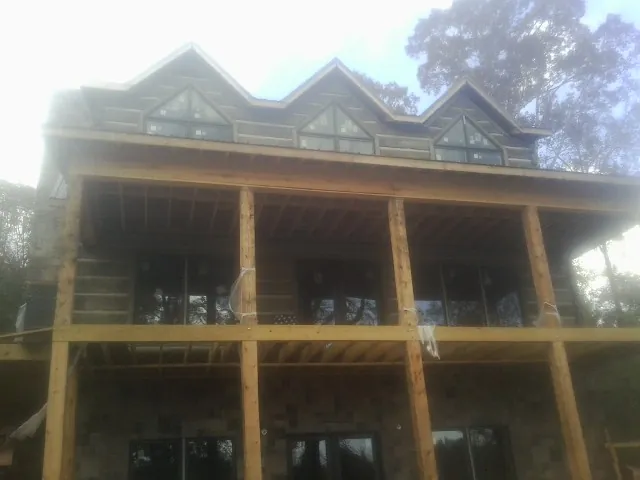 Dormers and porch framing on a large log home under construction — Roof Coating work by our crew in North Sioux City