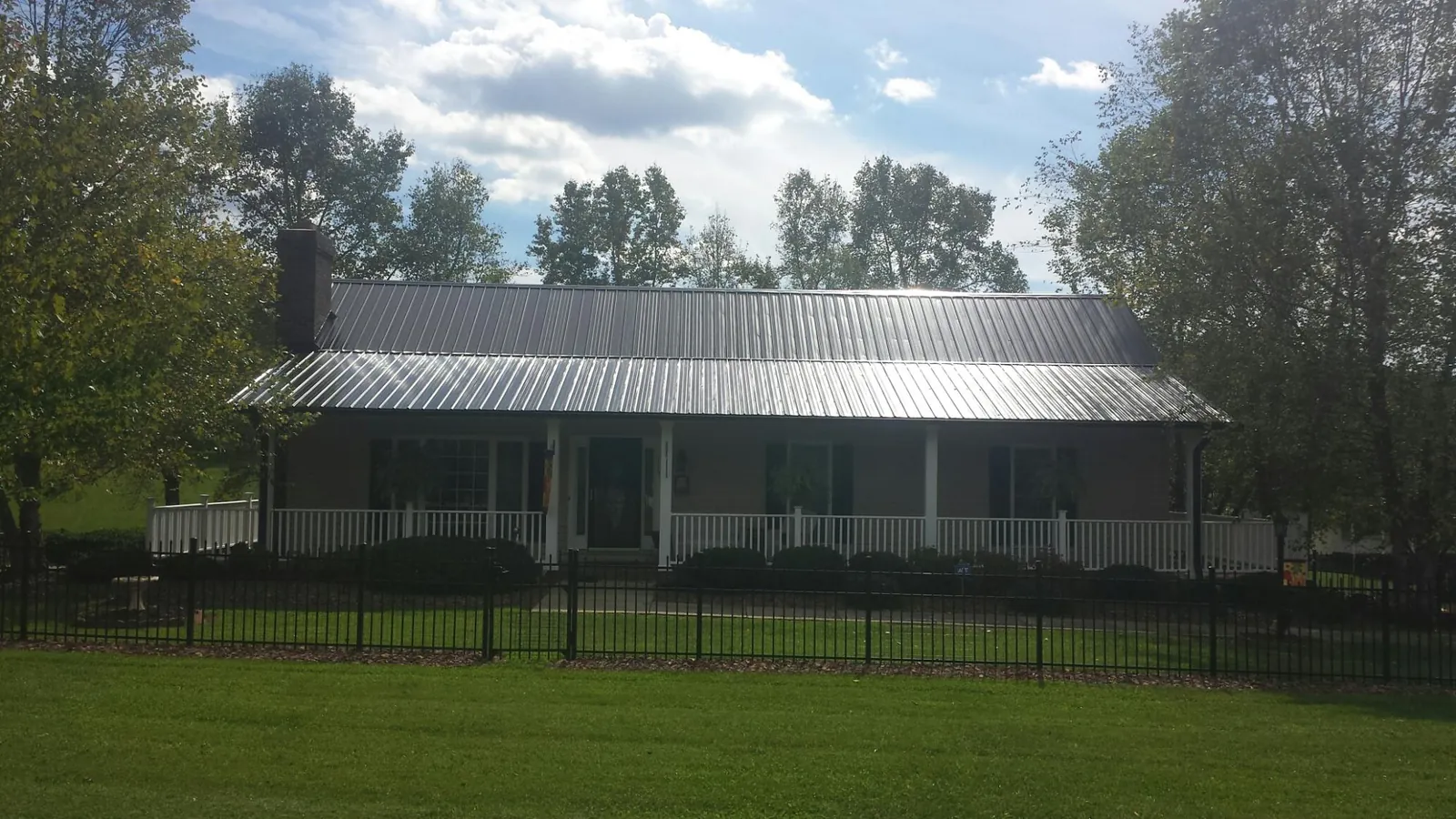 Gray metal roof on a brick ranch with a full width front porch — Gutter Guard Installation work by our crew in North Sioux City
