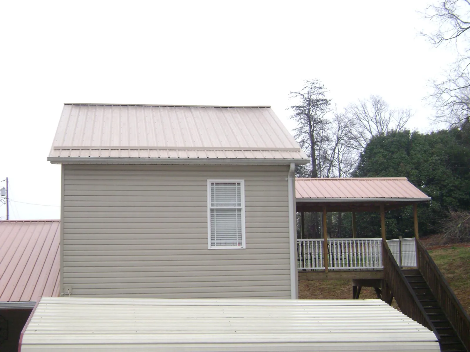 Tan metal roofs on a two story addition and attached porch, from a Roof Replacement job in North Sioux City