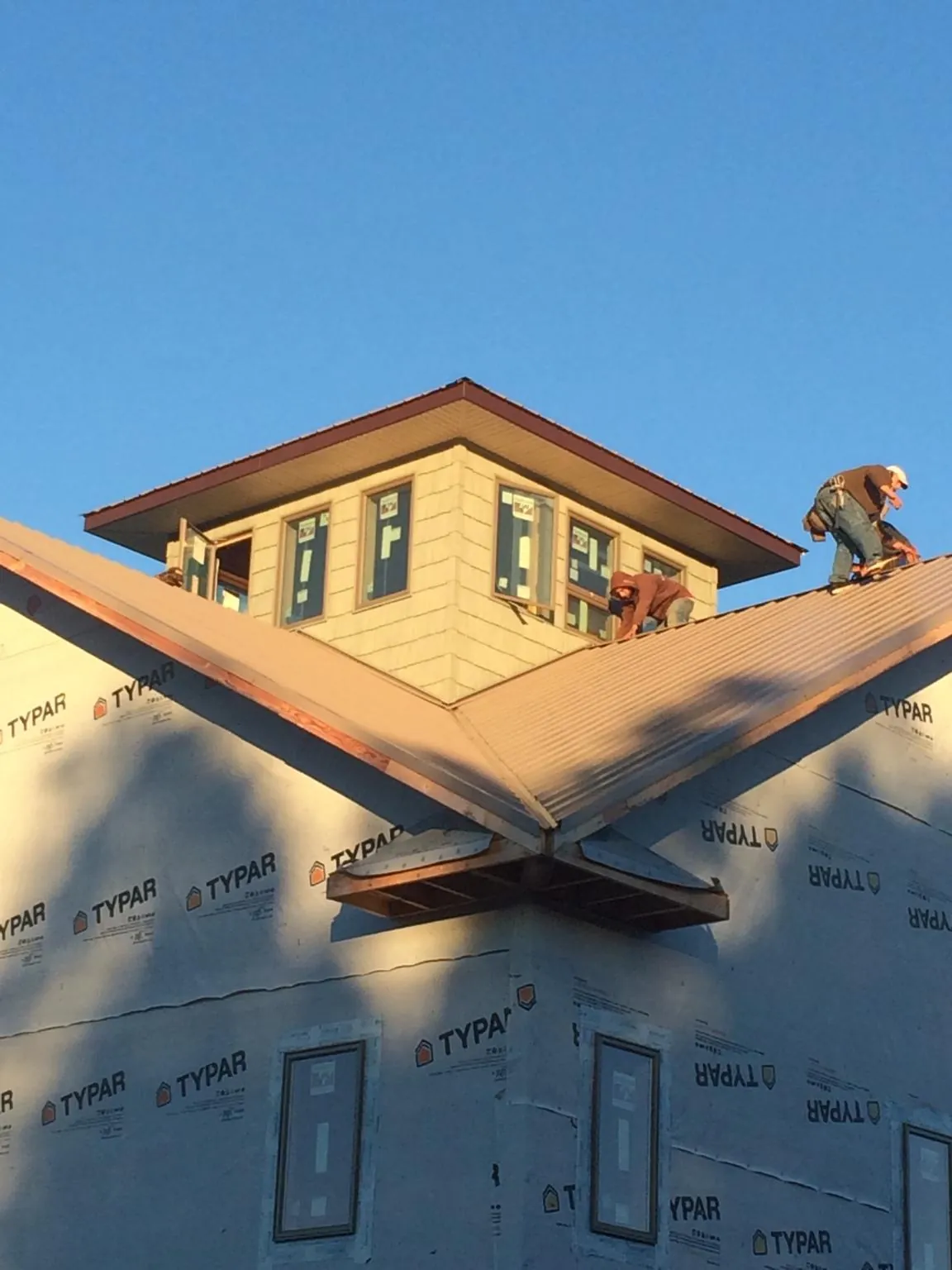 Roofers working around a rooftop cupola on a new metal roof at sunset — Roof Waterproofing in North Sioux City by Roofing Brothers